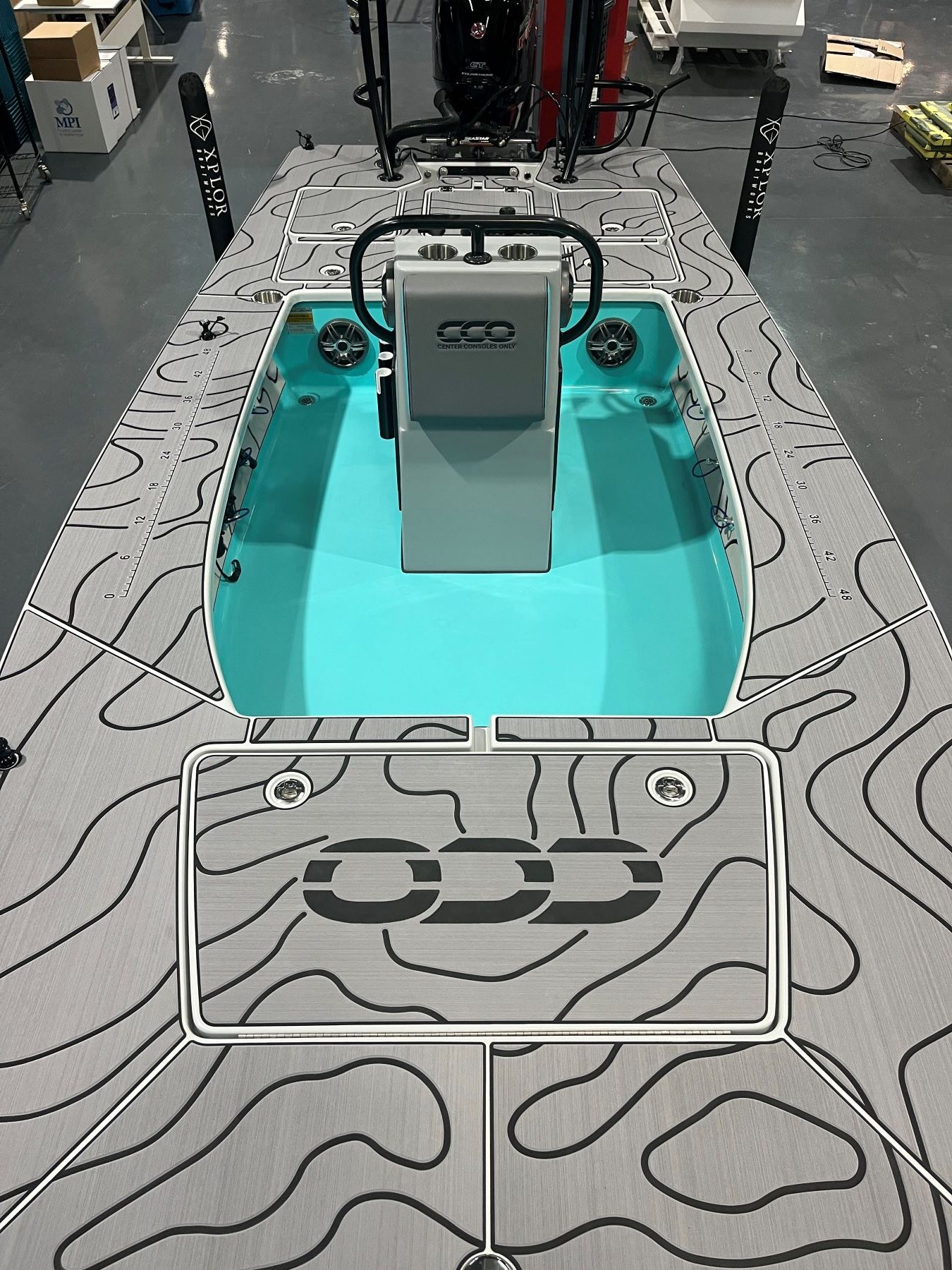 Skiff deck covered in Storm Gray SeaDek with a custom black topographic contour pattern, featuring a center console and bright aqua interior.