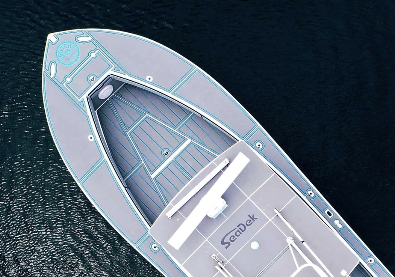 Drone shot of a regulator floating in the ocean. The regulator features a Storm Gray over Bahama Blue SeaDek kit with a custom logo at the bow of the boat.