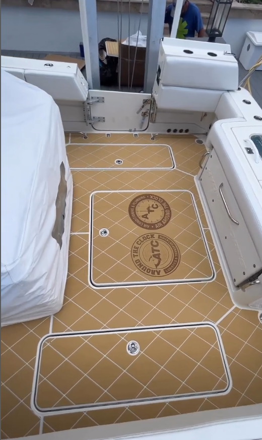 Boat deck with golden tan SeaDek flooring featuring diamond stitch pattern and engraved custom “Around The Clock” logos on the hatches.