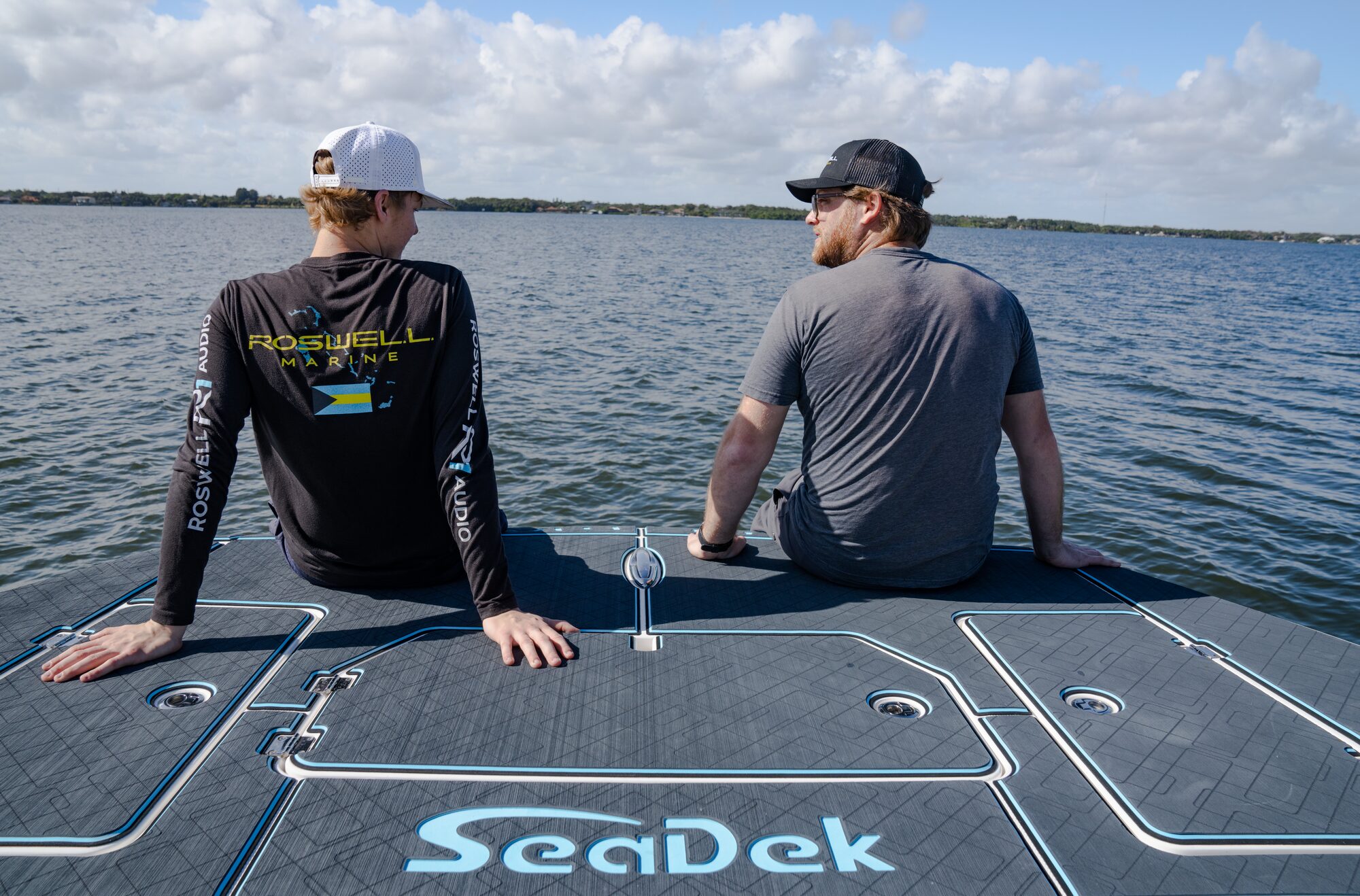 Two boaters sitting on a SeaDek covered deck enjoying a calm day on open water